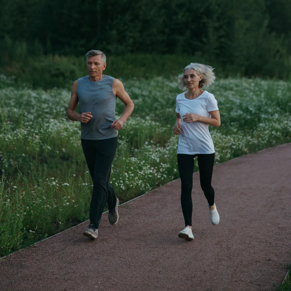 Two adults jogging together on a tree-lined outdoor path